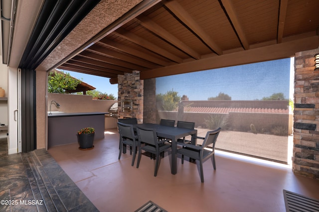 view of patio / terrace featuring fence, visible vents, exterior kitchen, and outdoor dining space