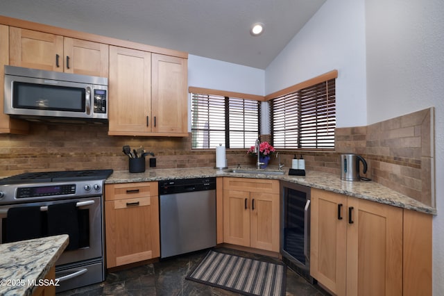 kitchen with lofted ceiling, wine cooler, light brown cabinets, a sink, and appliances with stainless steel finishes