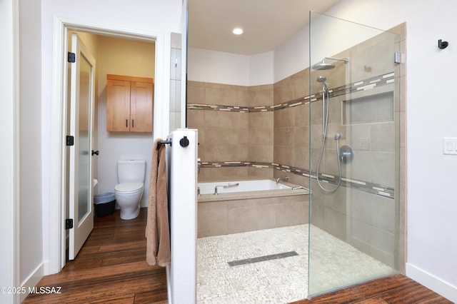 bathroom with toilet, a garden tub, wood finished floors, and a tile shower