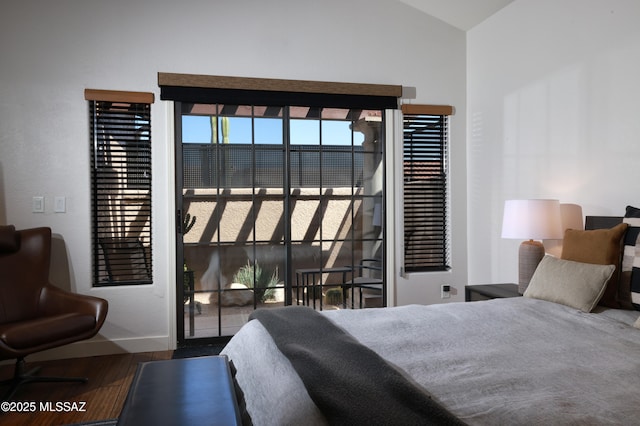 bedroom featuring wood finished floors, lofted ceiling, baseboards, and access to outside