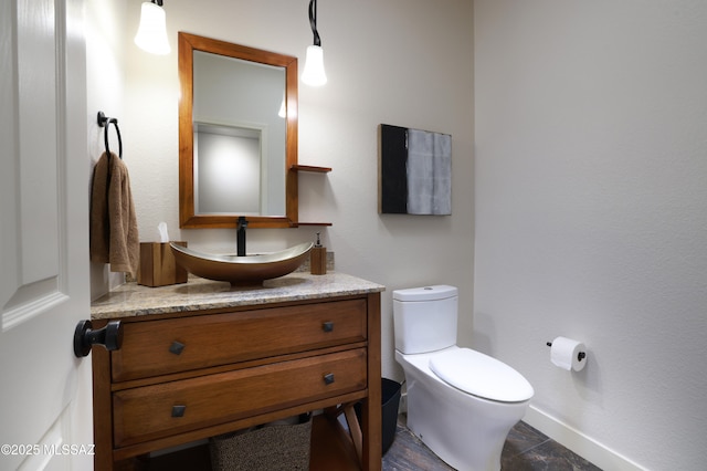 half bathroom featuring toilet, vanity, and baseboards