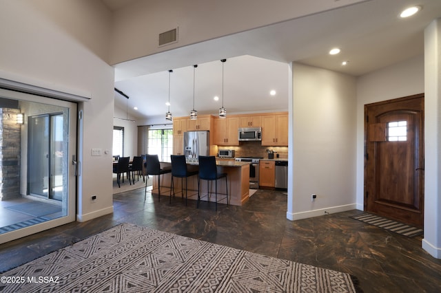 kitchen featuring light brown cabinetry, stainless steel appliances, a breakfast bar, visible vents, and baseboards