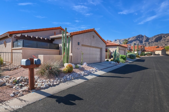 view of front of home featuring a tiled roof, stucco siding, an attached garage, driveway, and a mountain view