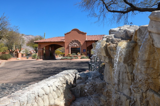 mediterranean / spanish house featuring a gate, a tile roof, stucco siding, and fence