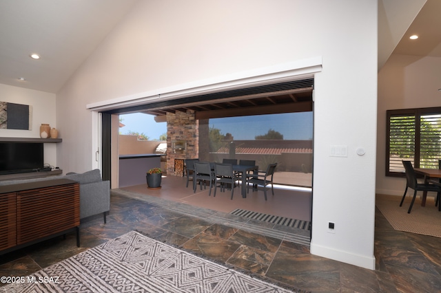 living area featuring high vaulted ceiling, recessed lighting, stone tile floors, and a healthy amount of sunlight
