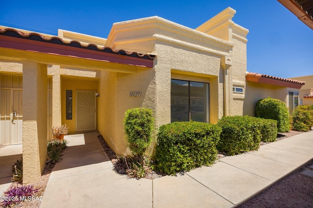 10127 E Achi, Tucson, AZ 85748 - view of exterior entry featuring stucco siding and a tile roof