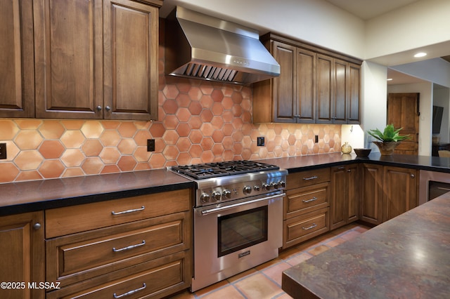 4915 N Via De La Granja, Tucson, AZ 85718 - kitchen featuring high end stainless steel range, wall chimney range hood, dark countertops, backsplash, and light tile patterned floors