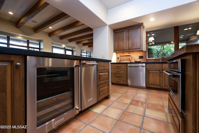 4915 N Via De La Granja, Tucson, AZ 85718 - kitchen featuring wine cooler, appliances with stainless steel finishes, beam ceiling, tasteful backsplash, and dark countertops
