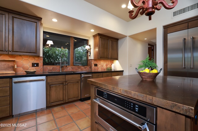 4915 N Via De La Granja, Tucson, AZ 85718 - kitchen with stainless steel dishwasher, dark countertops, tasteful backsplash, a chandelier, and a sink