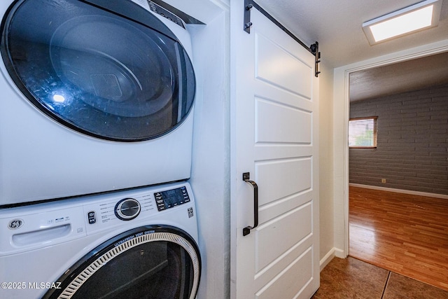 1652 W Roller Coaster Rd, Tucson, AZ 85704 - washroom featuring tile patterned floors, laundry area, stacked washing maching and dryer, baseboards, and brick wall