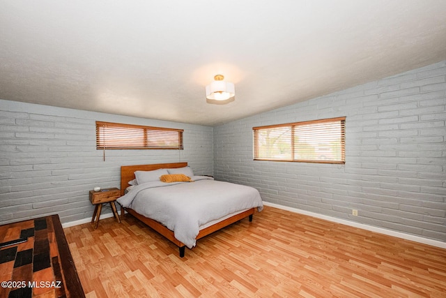 1652 W Roller Coaster Rd, Tucson, AZ 85704 - bedroom with brick wall, baseboards, lofted ceiling, and light wood finished floors