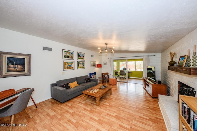 1652 W Roller Coaster Rd, Tucson, AZ 85704 - living area featuring visible vents, light wood-style flooring, a brick fireplace, and an inviting chandelier