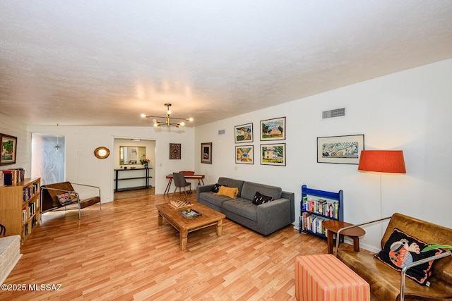 1652 W Roller Coaster Rd, Tucson, AZ 85704 - living room with light wood-style flooring, a textured ceiling, baseboards, visible vents, and a notable chandelier
