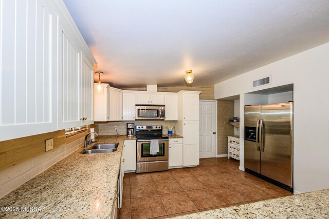 1652 W Roller Coaster Rd, Tucson, AZ 85704 - kitchen featuring light stone counters, a sink, stainless steel appliances, white cabinetry, and visible vents
