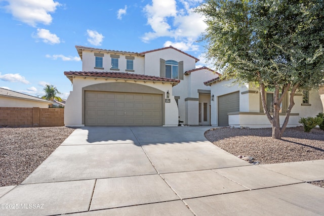 mediterranean / spanish-style house featuring concrete driveway, stucco siding, an attached garage, a tiled roof, and fence