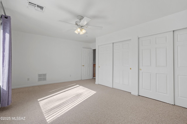 unfurnished bedroom featuring visible vents, baseboards, and two closets