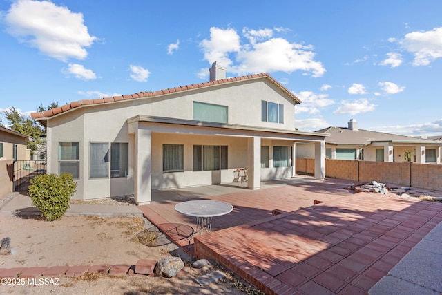 rear view of property featuring fence, a patio, stucco siding, and a chimney