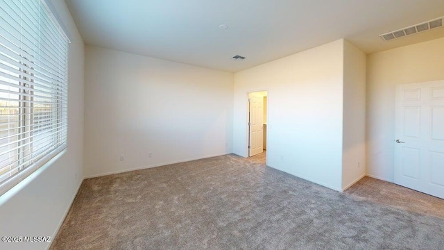 spare room with carpet flooring, baseboards, and visible vents