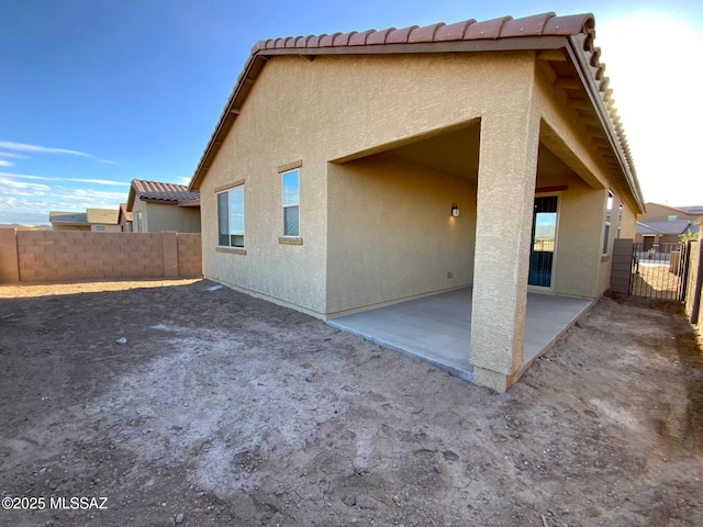 rear view of house featuring a patio, stucco siding, and fence