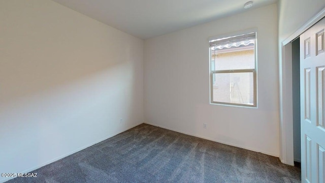 empty room with baseboards and dark carpet