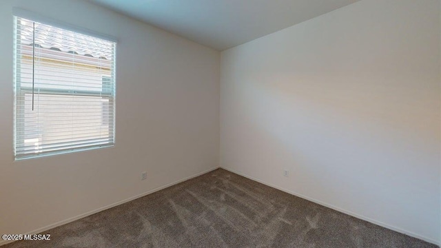 carpeted spare room with baseboards and vaulted ceiling