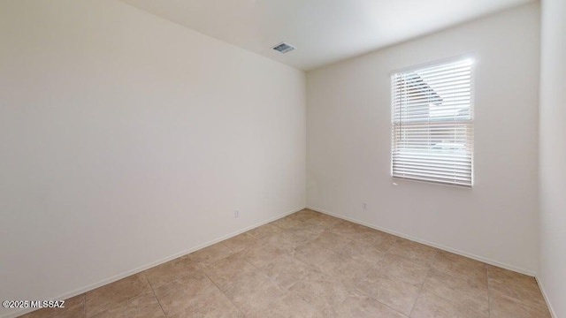 unfurnished room with a wealth of natural light, visible vents, and baseboards