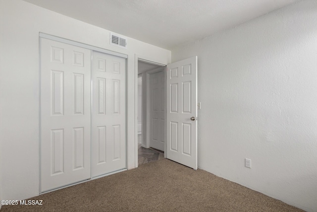 unfurnished bedroom with visible vents, carpet floors, and a closet