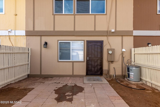 property entrance featuring fence, a patio, and water heater