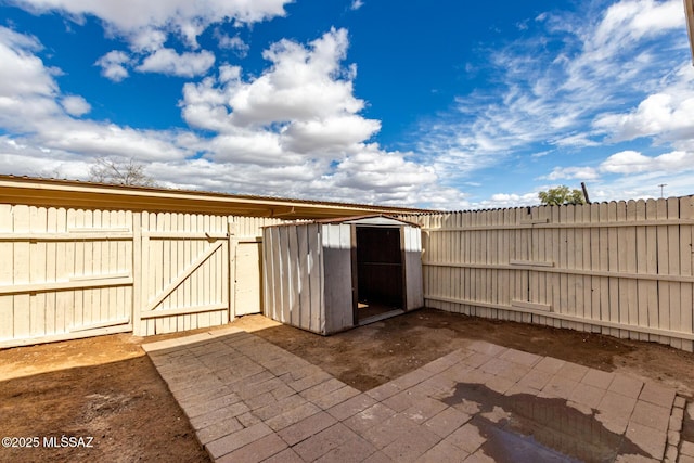 view of patio with a storage unit, a fenced backyard, a gate, and an outdoor structure