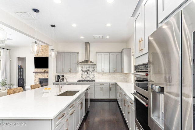 kitchen featuring visible vents, a sink, wall chimney exhaust hood, tasteful backsplash, and appliances with stainless steel finishes