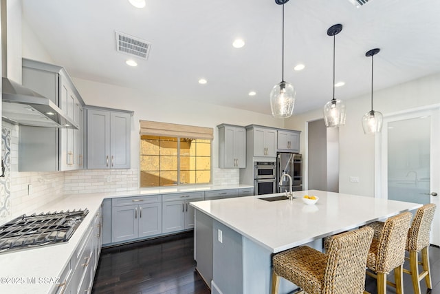 kitchen featuring backsplash, visible vents, dark wood-type flooring, wall chimney exhaust hood, and gray cabinetry