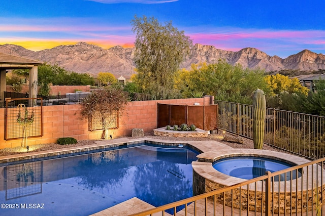 view of pool with a pool with connected hot tub, a fenced backyard, and a mountain view