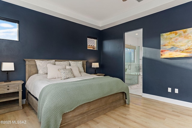 bedroom featuring wood finished floors, baseboards, and ensuite bathroom