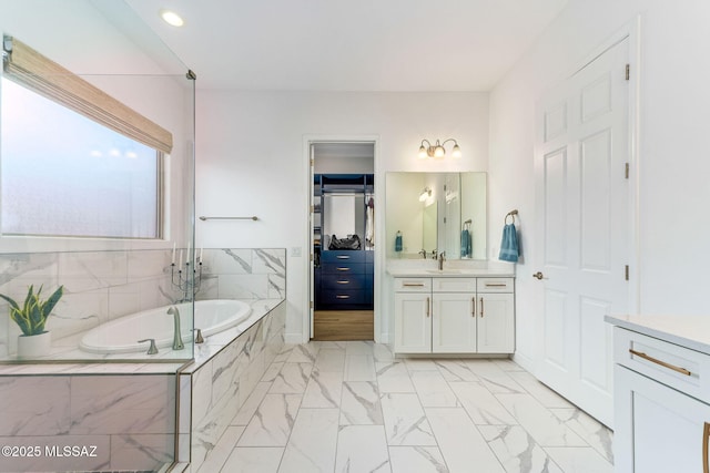 full bath with a garden tub, marble finish floor, recessed lighting, and vanity