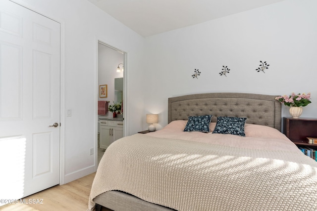 bedroom with connected bathroom and light wood finished floors