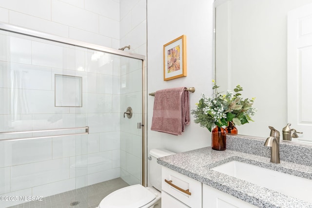 full bath featuring toilet, vanity, and a stall shower