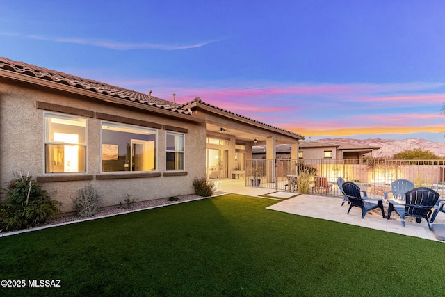 back of property featuring stucco siding, fence, a yard, and a patio
