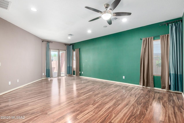 empty room featuring visible vents, a ceiling fan, and wood finished floors