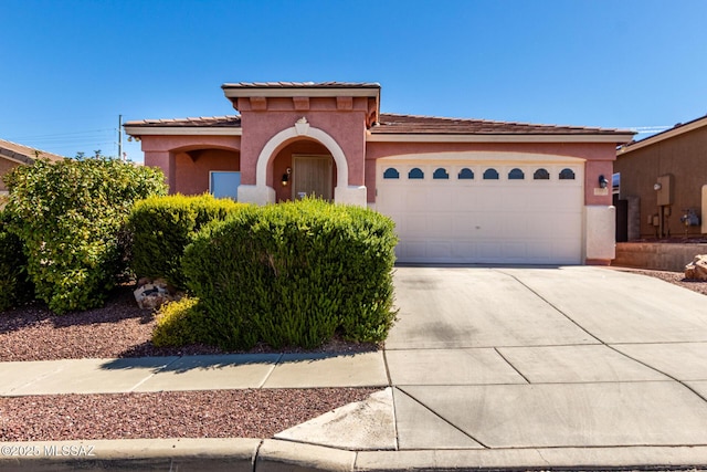 mediterranean / spanish home featuring a tiled roof, a garage, stucco siding, and concrete driveway