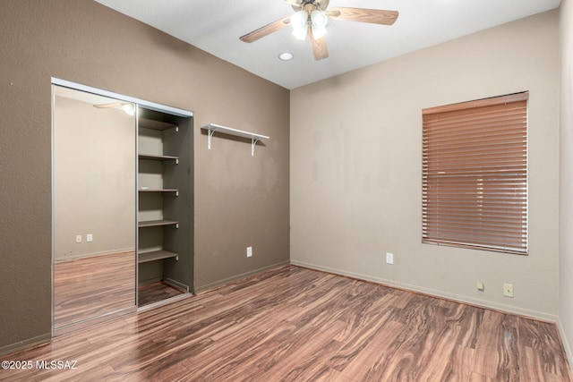 unfurnished bedroom with a ceiling fan, wood finished floors, baseboards, and a closet