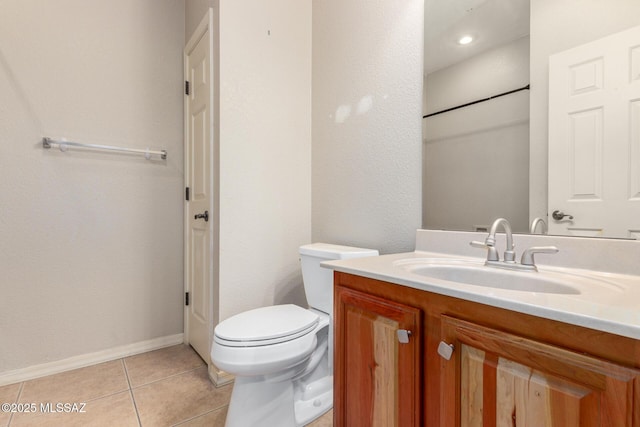 bathroom with toilet, vanity, baseboards, and tile patterned flooring