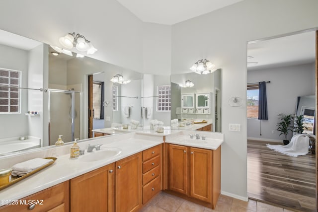 full bathroom with a bath, a sink, double vanity, and a stall shower