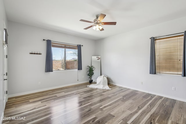 unfurnished room with wood finished floors, ceiling fan, and baseboards