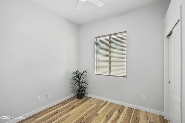 unfurnished bedroom featuring light wood-style floors, a closet, baseboards, and a ceiling fan