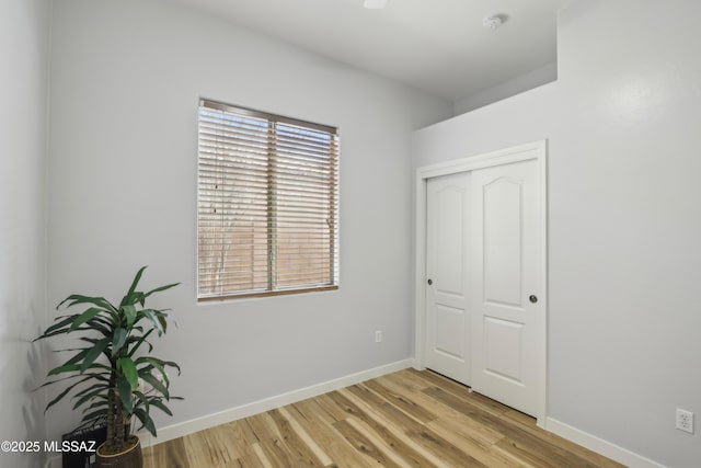 unfurnished bedroom featuring a closet, baseboards, and light wood-style floors