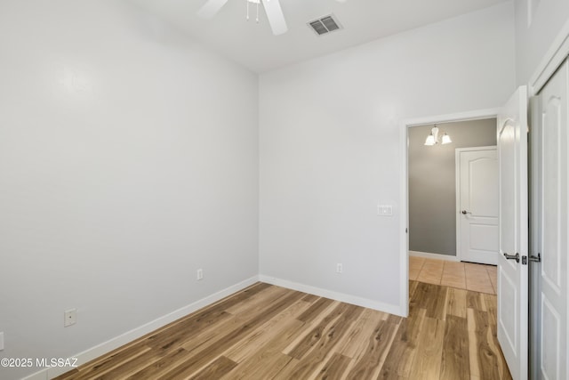 spare room featuring light wood finished floors, visible vents, a ceiling fan, and baseboards