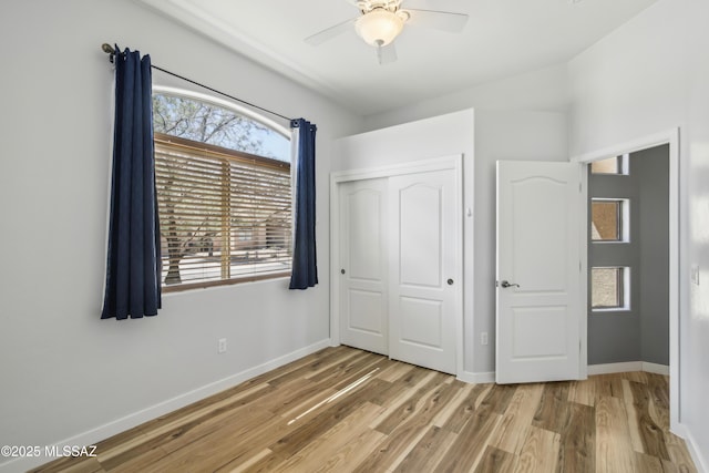 unfurnished bedroom featuring a closet, light wood-type flooring, baseboards, and a ceiling fan