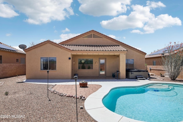 rear view of property featuring a hot tub, stucco siding, a patio, fence, and a tile roof