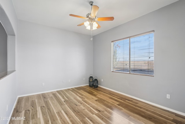 unfurnished room featuring arched walkways, wood finished floors, baseboards, and ceiling fan