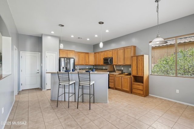 kitchen with stainless steel appliances, a kitchen island with sink, light tile patterned floors, and hanging light fixtures